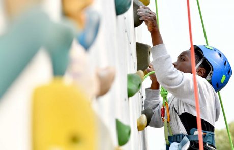 menino escala parede com ajuda de monitores e cordas