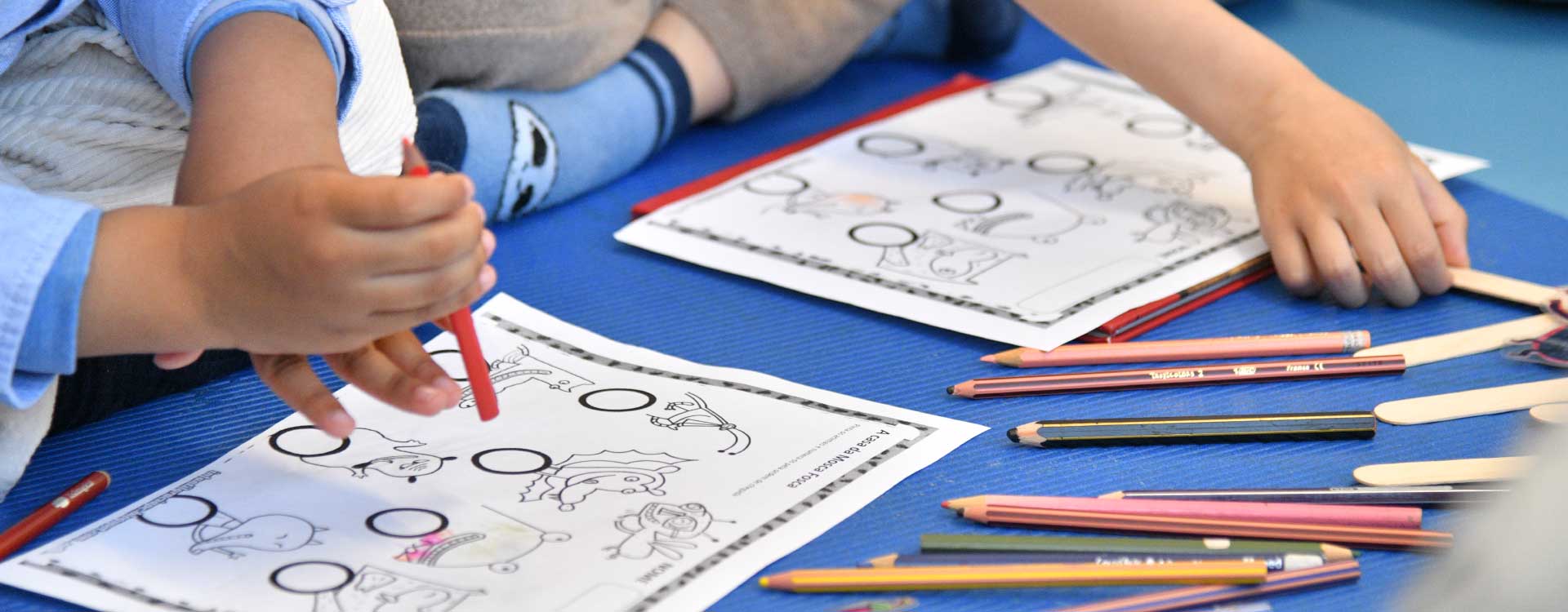 crianças pintam papeis com lápis de cera