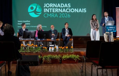 Especialista intervém ao púlpito, acompanhado por uma mulher e quatro participantes sentados, numa sessão dedicada à formação em reabilitação.