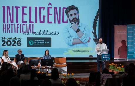 Nestor Guerra apresenta uma sessão sobre inteligência artificial na reabilitação, perante o público e três participantes sentados no palco.